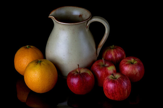 Earthenware Jug with Apples and Oranges on a Shiny Black Surface