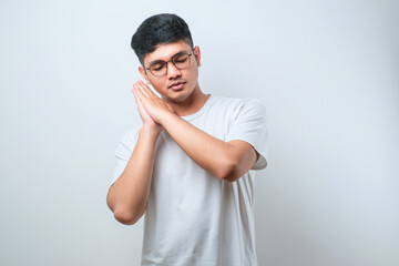 Fototapeta premium Asian handsome man wearing shirt sleeping tired dreaming and posing with hands together while smiling with closed eyes