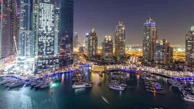 Dubai Marina skyscrapers aeral day to night transition panoramic timelapse, port with luxury yachts and marina promenade, Dubai, United Arab Emirates. Illuminated towers and traffic on the road