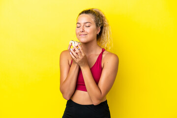 Girl with curly hair isolated on yellow background holding a donut