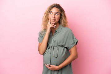 Girl with curly hair isolated on pink background pregnant and thinking