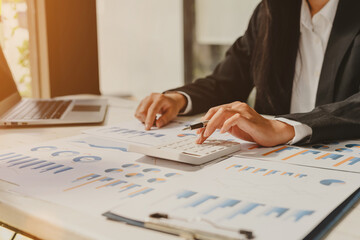 Close up Business woman using calculator and laptop for do math finance on wooden desk in office and business working background, tax, accounting, statistics and analytic research concept