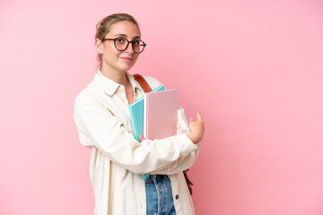Young student caucasian woman isolated on pink background pointing back