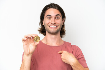 Young handsome man holding a Bitcoin isolated on white background with surprise facial expression