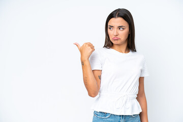 Young caucasian woman isolated on white background unhappy and pointing to the side