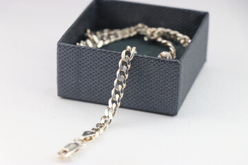 Silver chain with details of chain links out of the box that is worn as a necklace or fashion jewelry kept in a box on white background - obrazy, fototapety, plakaty