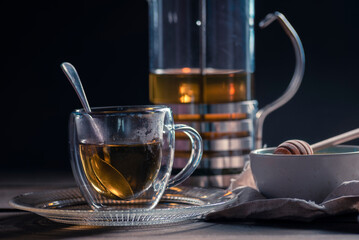 Herbal mint tea cup Transparent glass dark background wooden table still life honey bowl metal kettle teapot spoon cozy