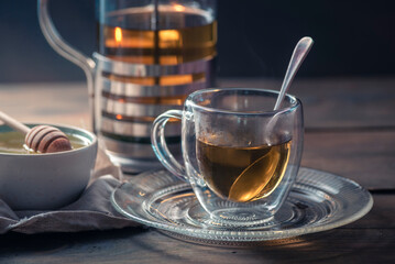 Herbal mint tea cup Transparent glass dark background wooden table still life honey bowl metal kettle teapot spoon cozy