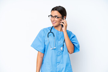 Young nurse woman isolated on white background keeping a conversation with the mobile phone with someone