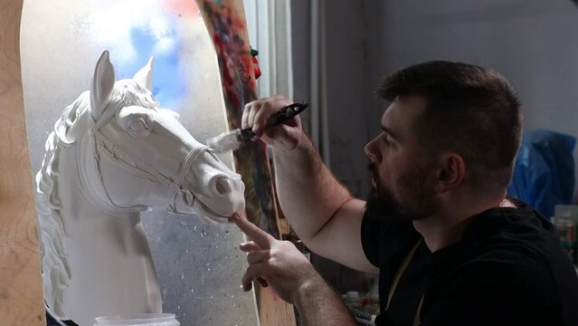 Artisan craftsman create horse based on plaster cast. Gypsum mold and plastic mask sculpting and painting