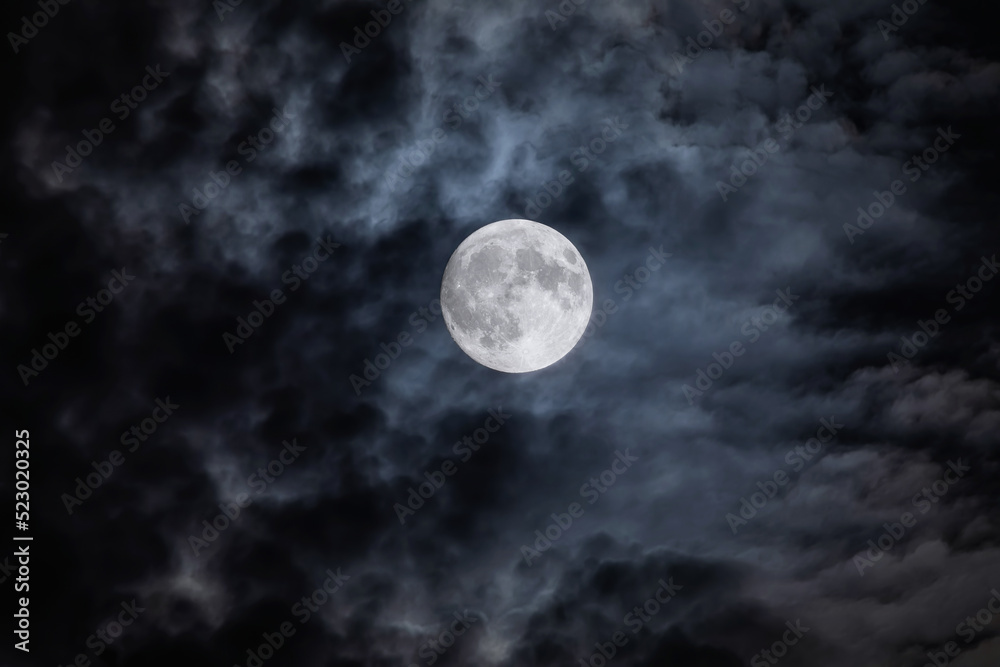 Wall mural full moon at night. the illuminated face of the moon is wrapped in a cloud cover that covers it in a