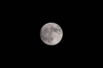 Full moon at night. Close-up of the bright full moon in the night. On the lunar surface the seas; the flat areas and the lunar craters are clearly visible.