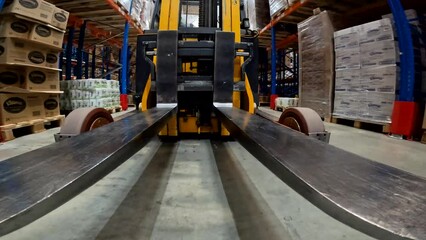 Forklift fork close-up. The load lifter rides on the warehouse pov. Modern forklift in a large warehouse