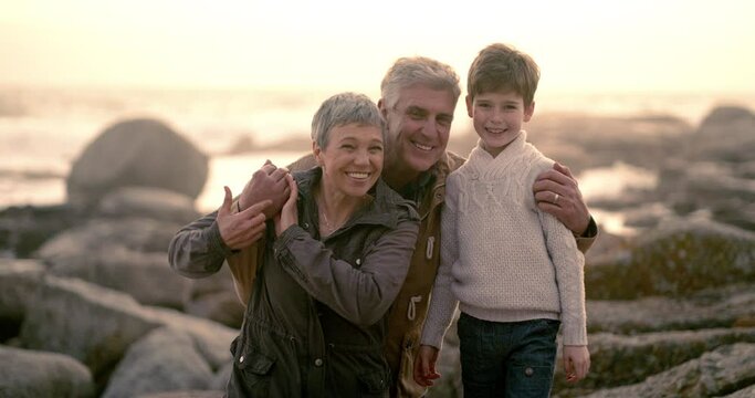 Bonding, holiday photo with grandparents smiling with grandson for a picture at the sea on the rocks. Grandfather and grandmother taking a lovely and happy portrait with their little grandchild.