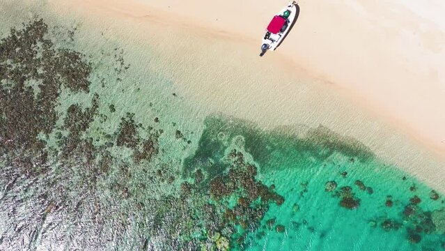 Aerial Top Shot Of Boat Moored At Island Beach By Turquoise Sea, Drone Flying Upwards On Sunny Day - Great Barrier Reef, Australia