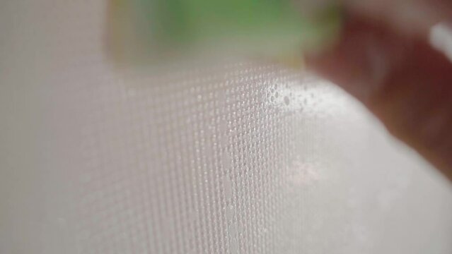 A glass opaque window being washed with a sponge and soapy water close-up