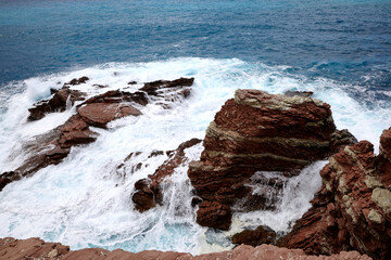 Rough sea against red rocks