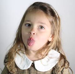 Cheerful little girl puts out the tongue on white background