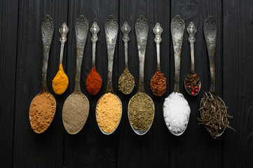 Colorful various herbs and spices for cooking on dark wooden rustic background