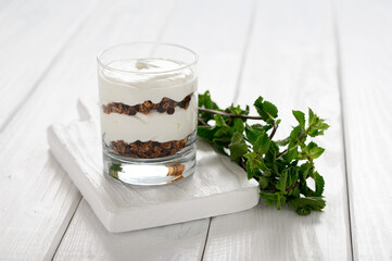 Dessert with mascarpone cheese and granola on a white wooden background.
