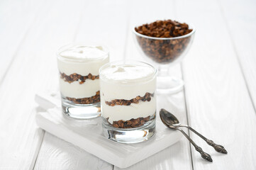 Dessert with mascarpone cheese and granola on a white wooden background.