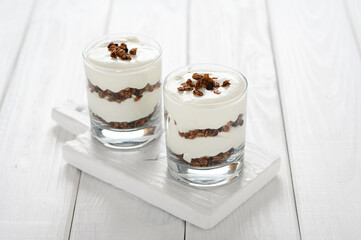 Dessert with mascarpone cheese and granola on a white wooden background.