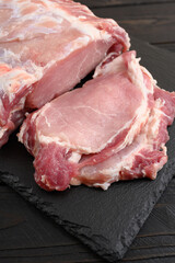A large piece of pork loin on a rustic dark background.