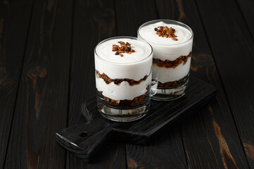 Layered dessert with granola on a wooden dark wooden background.