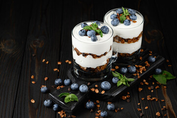 Dessert with mascarpone cheese, fresh blueberries and muesli in a glass on a rustic background.