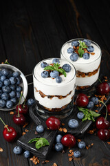 Homemade layered dessert with fresh blueberry, cherry, cream cheese or yogurt, granola.