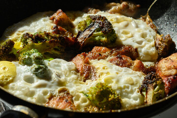 Beef meat, chicken eggs and broccoli vegetables being cooked in a frying pan close-up
