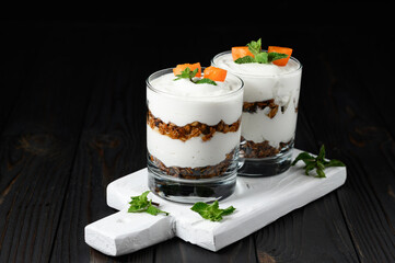 Homemade layered dessert with fresh apricot, cream cheese or yogurt, granola on rustic background.
