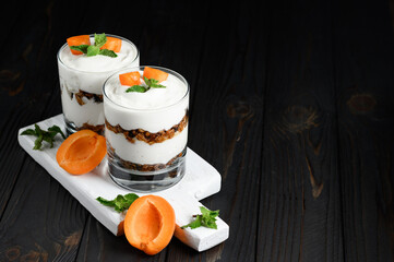 Homemade layered dessert with fresh apricot, cream cheese or yogurt, granola on rustic background.