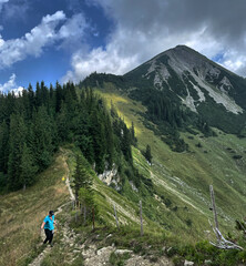 Bergwanderer (weiblich) auf dem Weg zum Breitenstein mit dem Gipfel des Geigelstein im Hintergrund,...