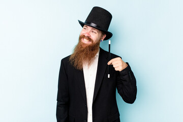 Young magician man isolated on blue background looks aside smiling, cheerful and pleasant.