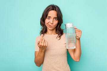 Young hispanic woman holding a water of jar isolated on blue background pointing with finger at you as if inviting come closer.