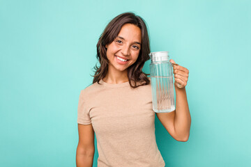 Young hispanic woman holding a water of jar isolated on blue background happy, smiling and cheerful.