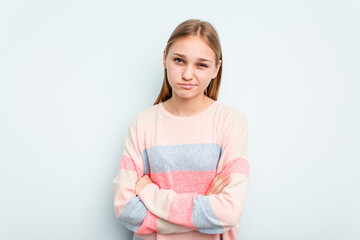 Young caucasian girl isolated on blue background frowning face in displeasure, keeps arms folded.