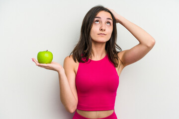 Young caucasian woman holding an apple isolated on white background being shocked, she has remembered important meeting.