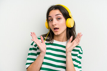 Young caucasian woman listening to music isolated on white background surprised and shocked.