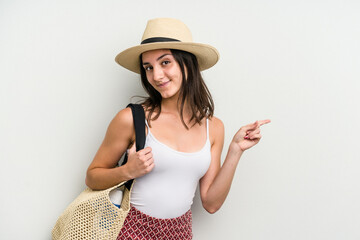 Young caucasian woman wearing a beach bag isolated on white background smiling and pointing aside, showing something at blank space.