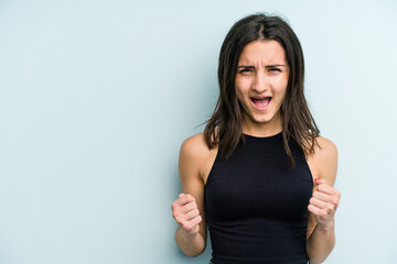 Young caucasian woman isolated on blue background shouting very angry, rage concept, frustrated.