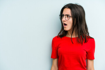 Young caucasian woman isolated on blue background shouting very angry, rage concept, frustrated.