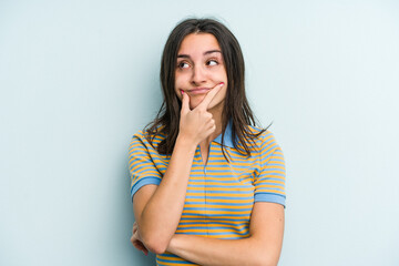Fototapeta premium Young caucasian woman isolated on blue background doubting between two options.