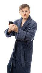 Fototapeta premium portrait of a man in a gray terry bathrobe. a man in home clothes is holding a phone and is surprised. rest at home. isolated.