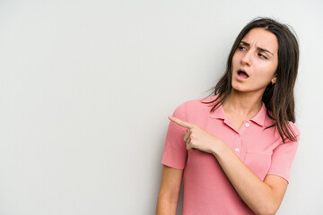 Young caucasian woman isolated on white background points with thumb finger away, laughing and carefree.