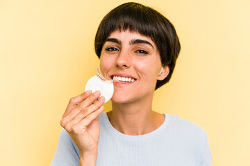 Young caucasian woman holding teeth whitener isolated on yellow background