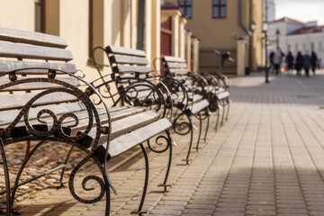 Fototapeta na wymiar row of benches on an old street in the city, sunny summer day, copy space