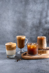 Espresso Tonic, cold drink with espresso and tonic in glass. Ice coffee in a tall glass with cream poured over and coffee beans. Set with different types of coffee drinks on a dark table.