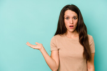 Fototapeta premium Young caucasian woman isolated on blue background impressed holding copy space on palm.